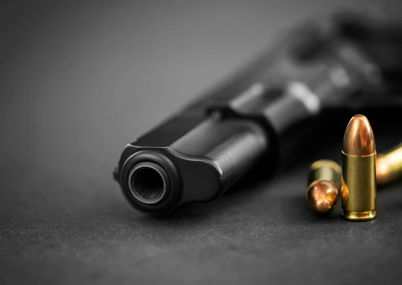Handgun with bullets on dark surface