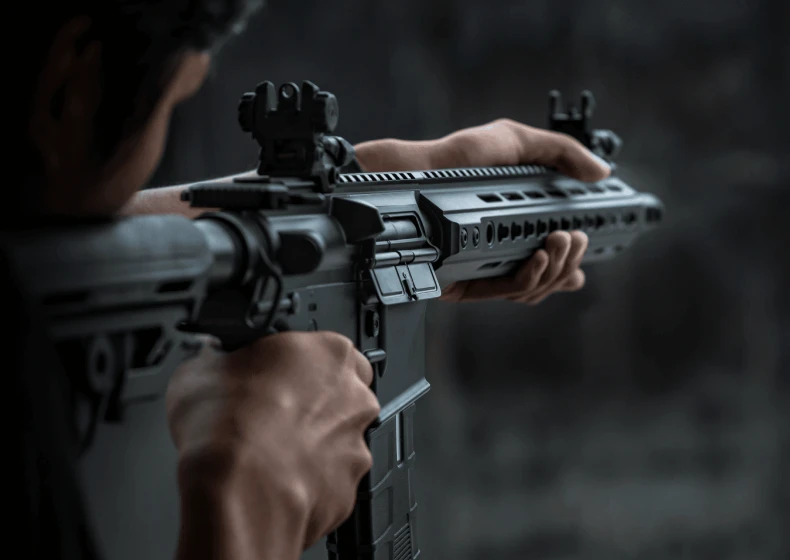Person aiming a rifle outdoors