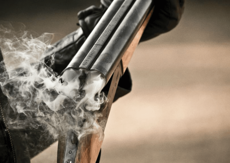 Close-up of a smoking shotgun barrel after firing.